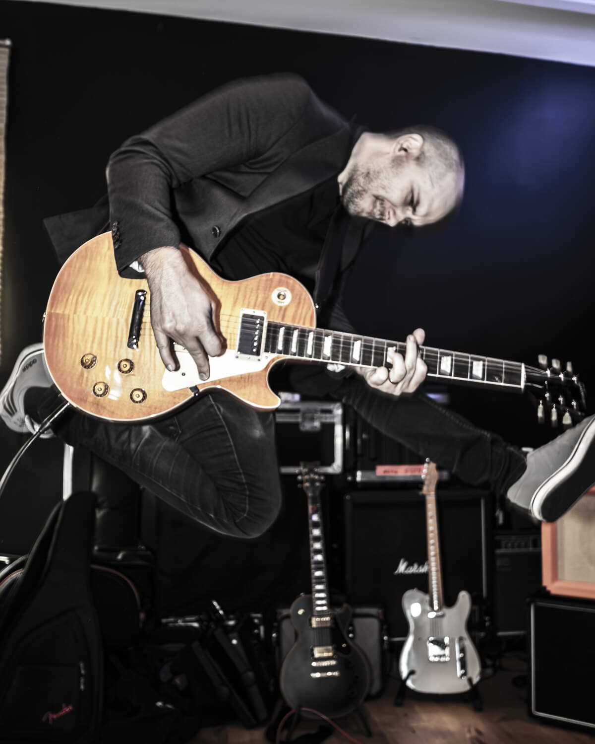 Philip K. Gisslow, mid-air with a Les Paul, on a video shoot with his band